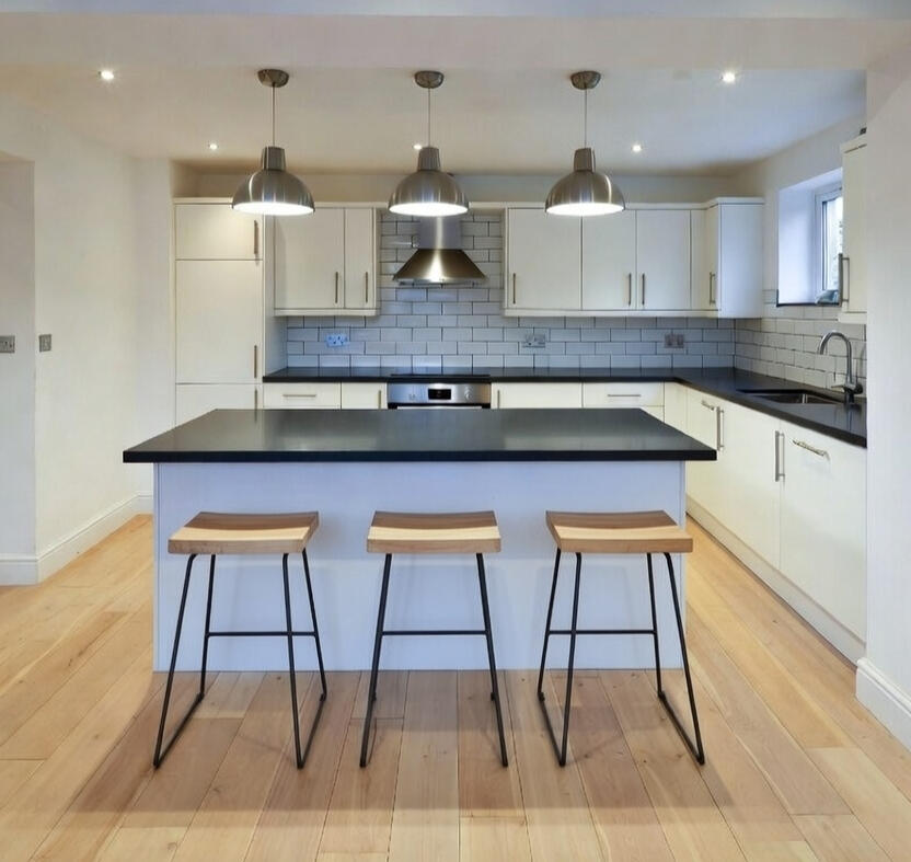 White kitchen with dark island, three bar stools and pendant lights White kitchen with dark island, three bar stools and pendant lights
